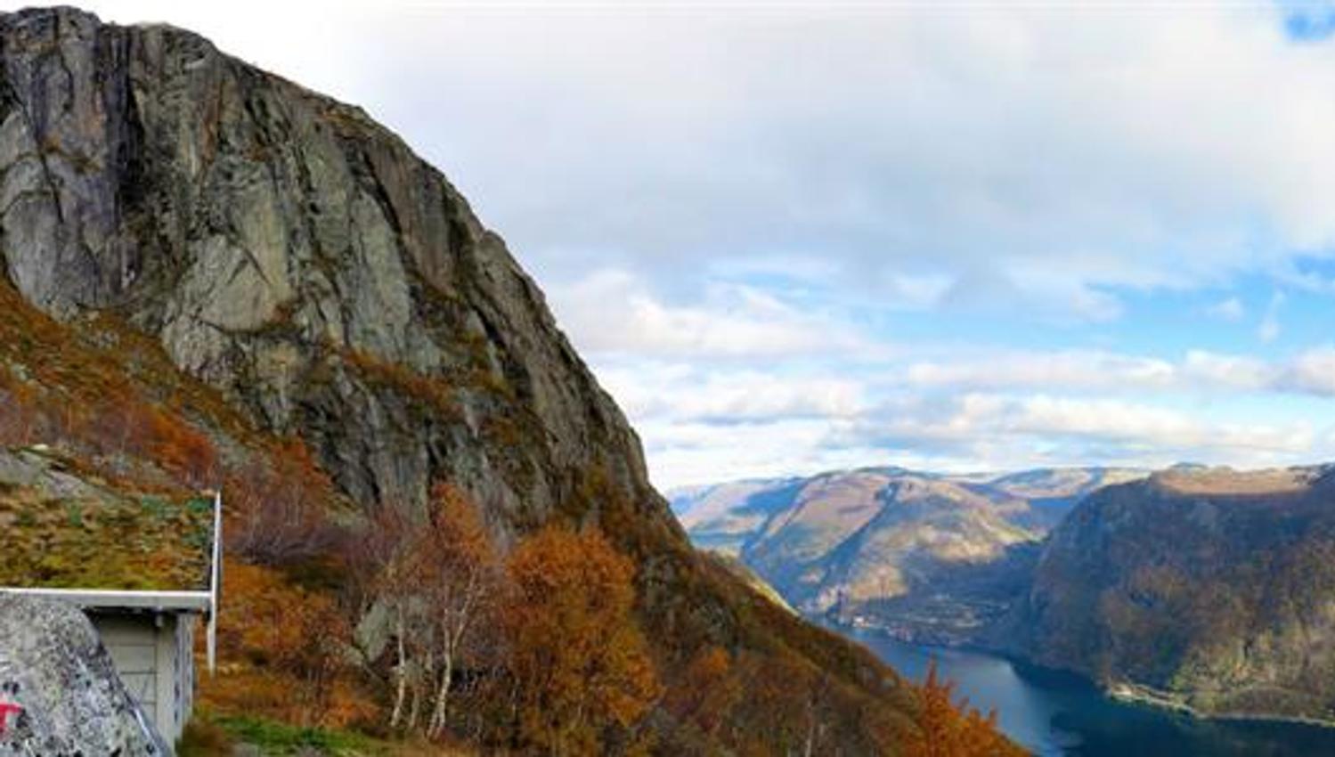 View from Tokheimsnuten on the Tourist Route to Folgefonna, featuring a trail marker, autumn-coloured birch forest, steep cliffs and a deep view over