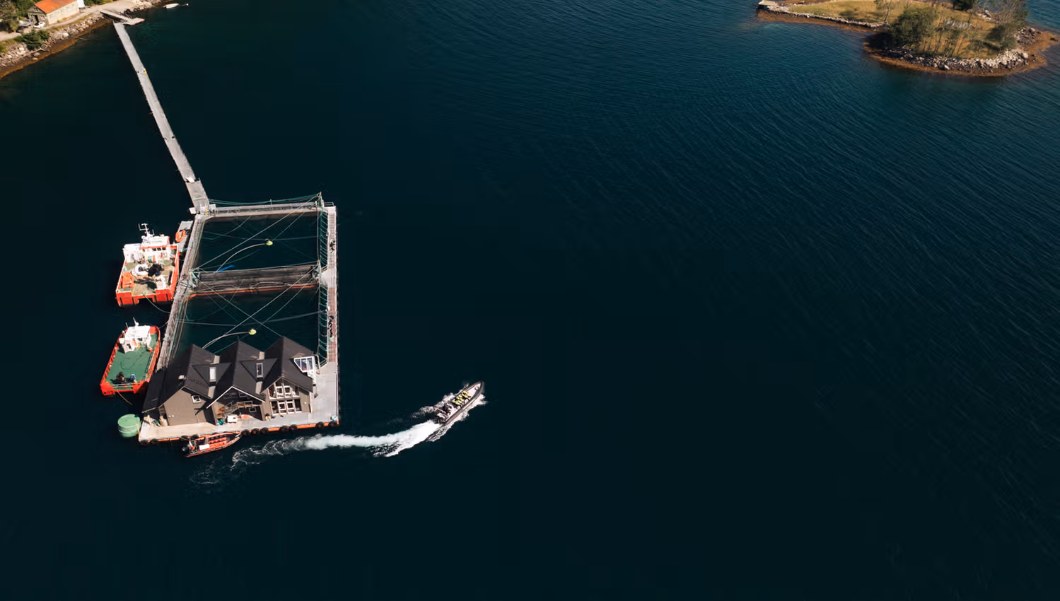 Luftaufnahme des Hardanger Aquakulturzentrums mit Lachsfarm und Booten im Hardangerfjord.