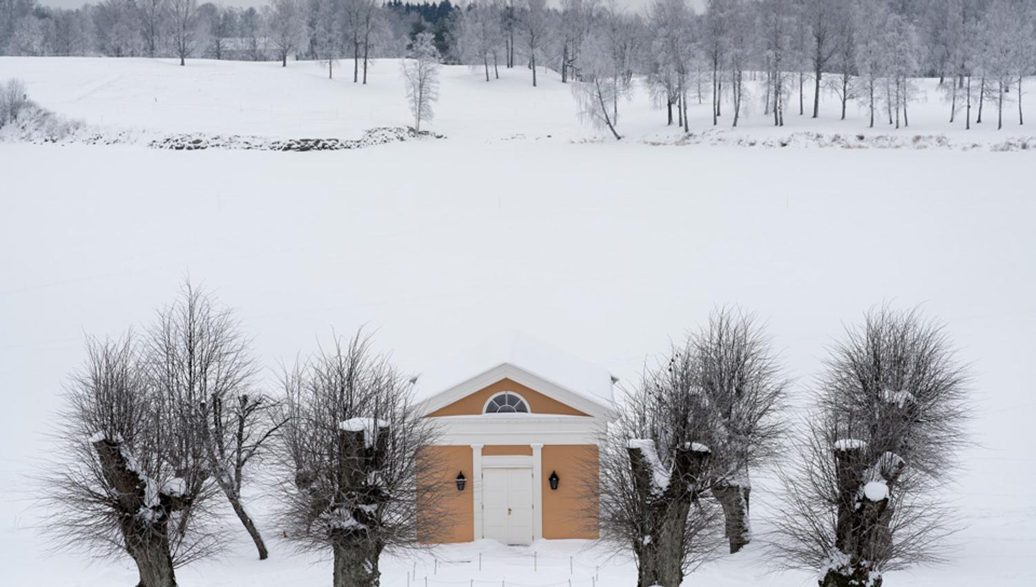 A small yellow house in a snow-covered scenery.