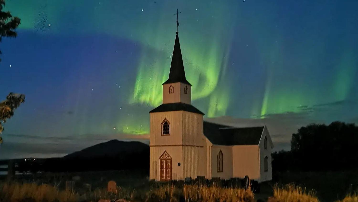 tradisjonell kirke med nordlys himmel over seg