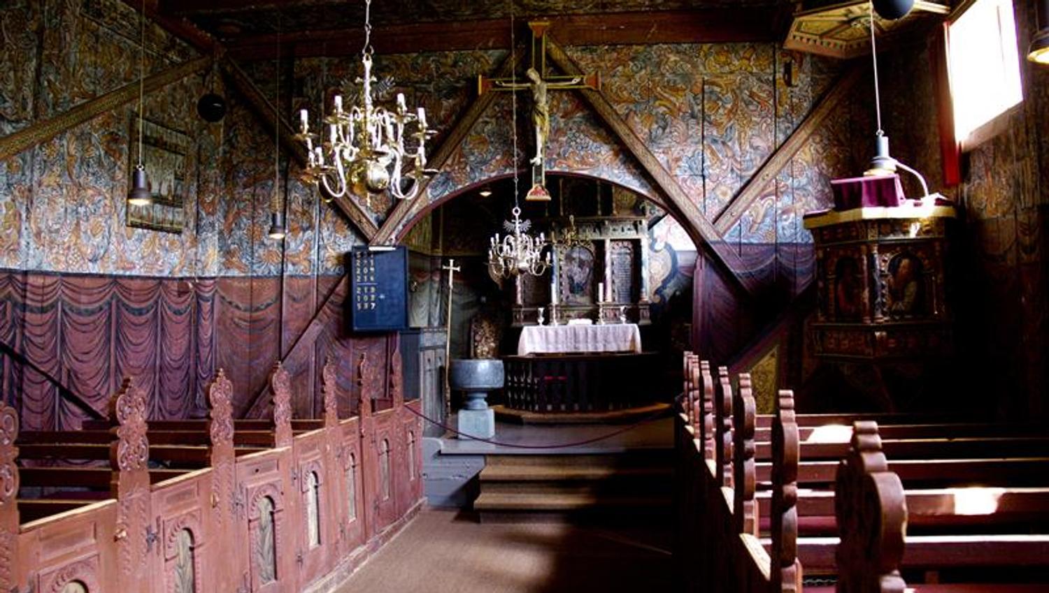 Richly painted interior of Røldal Stave Church featuring the altar, wood carvings, and medieval details.