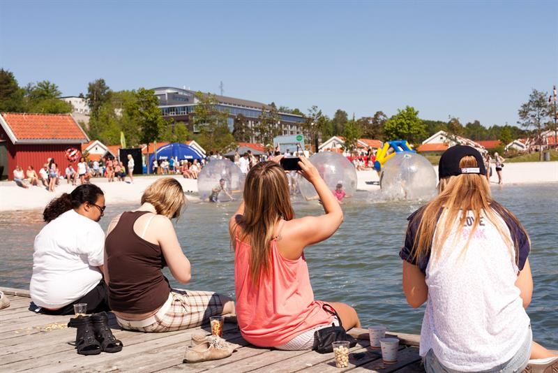 Folk sitter på brygga ved vannet