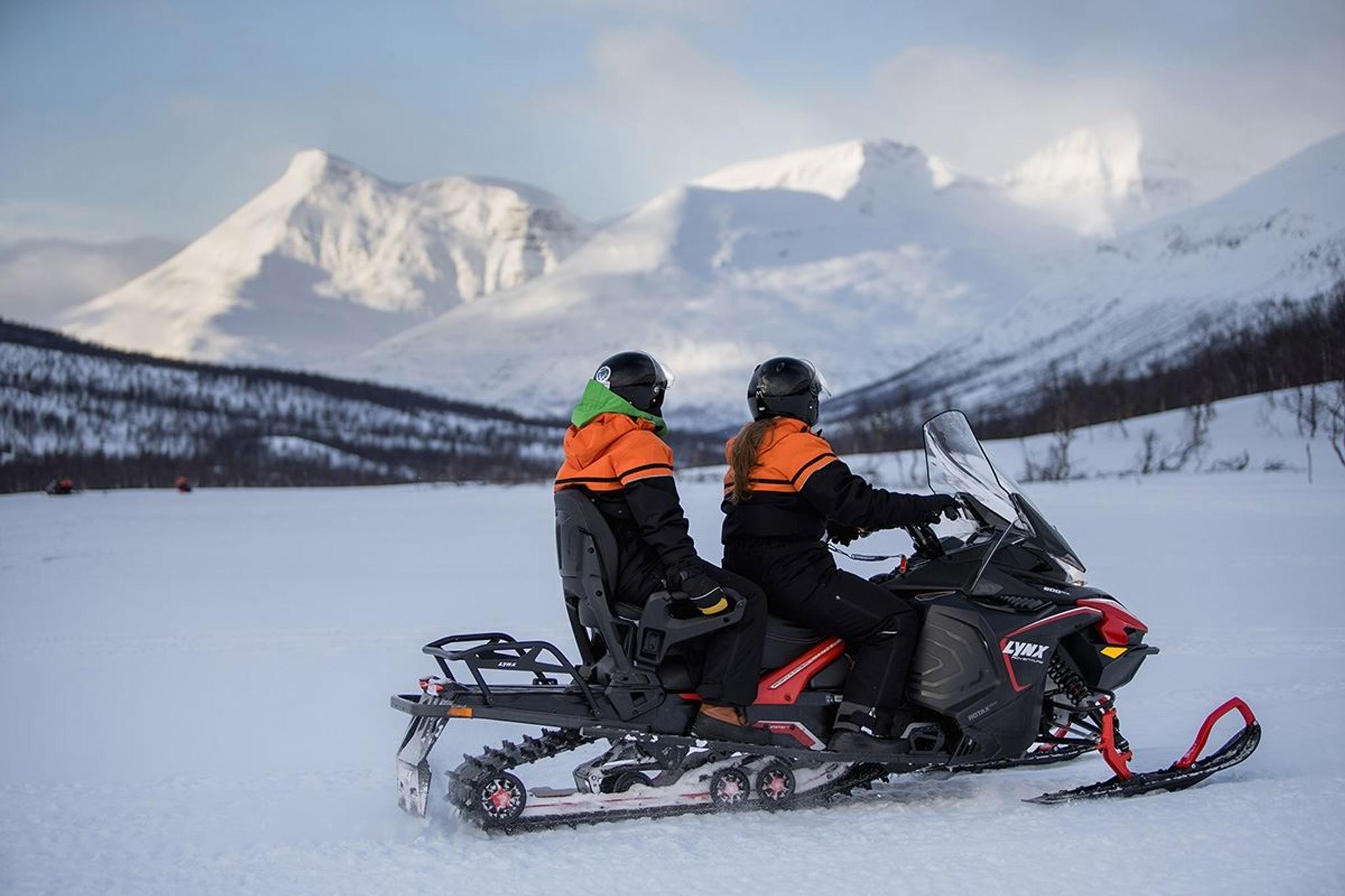Gjester ser ut over de vakre fjellene fra snøskuteren