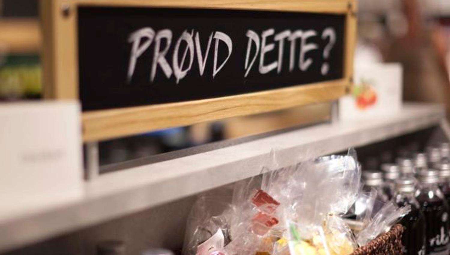 A sign reading “Tried this?” stands above a store shelf filled with bottles and packaged goods. The sign invites customers to try or buy something new