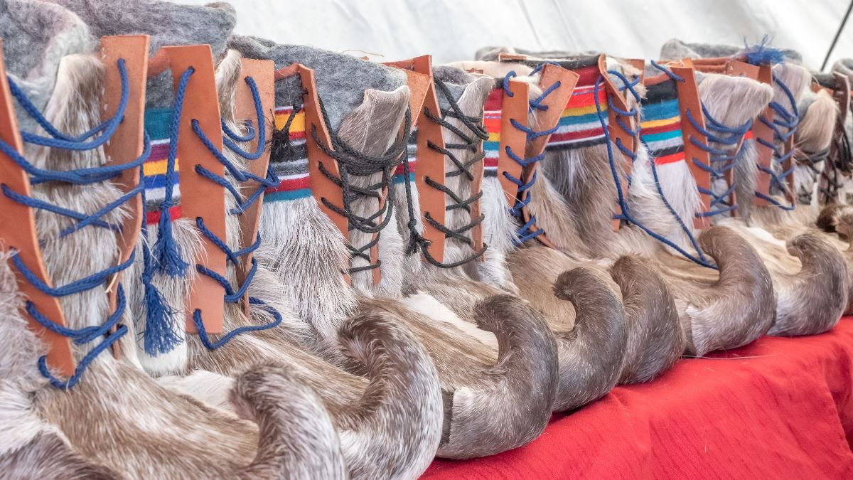 Traditional Sámi shoes with colourful details displayed in a row.