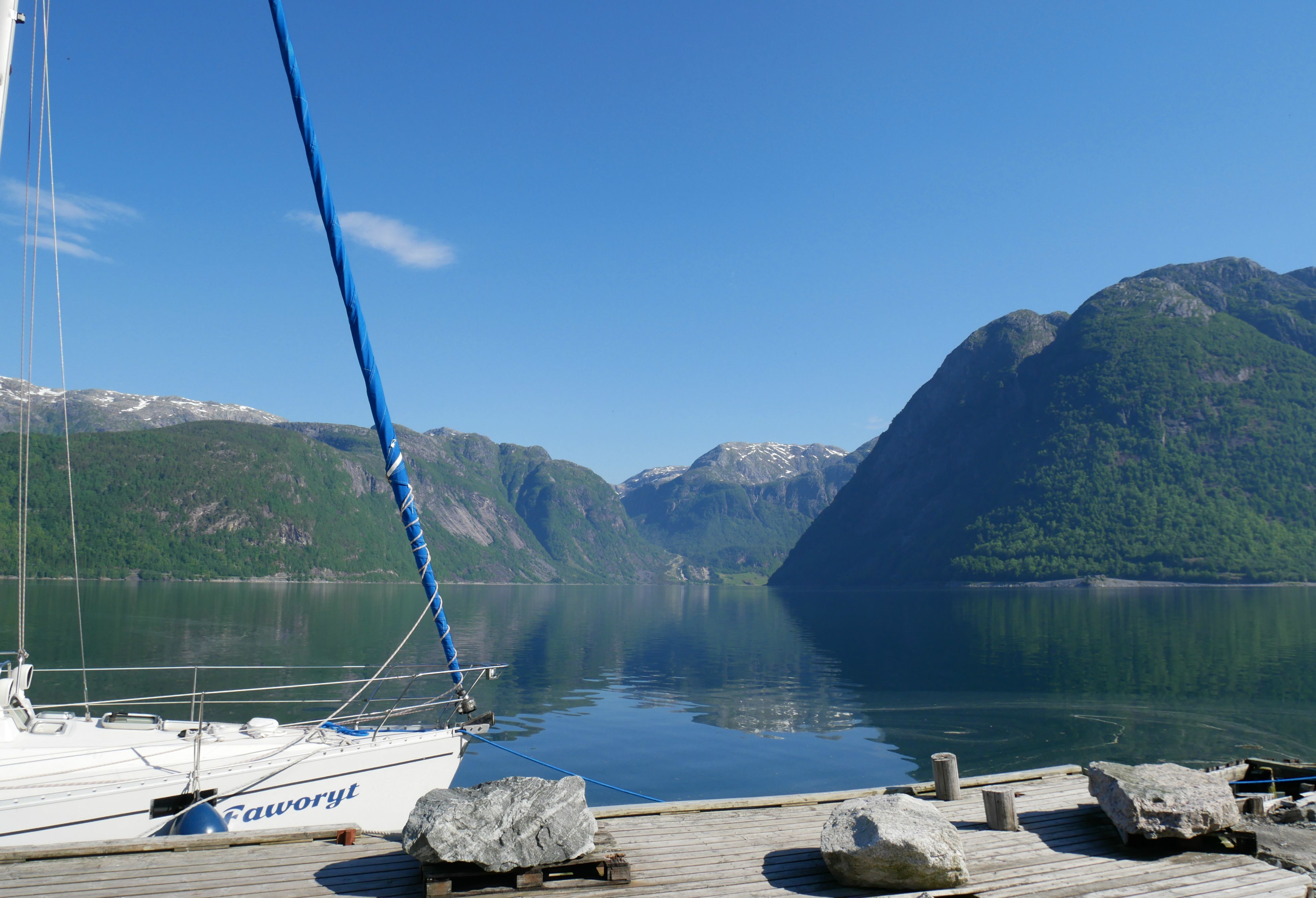 Båtplass ved fjorden med roleg vatn og natur rundt campingområdet i Hardanger.