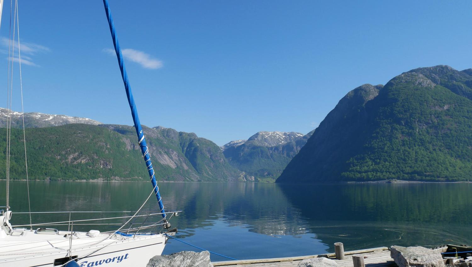 Båtplass ved fjorden med roleg vatn og natur rundt campingområdet i Hardanger.