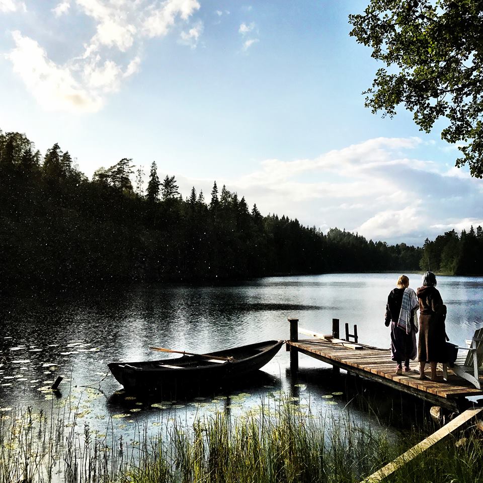 two women by the water on a doc, ready to go swimming 
