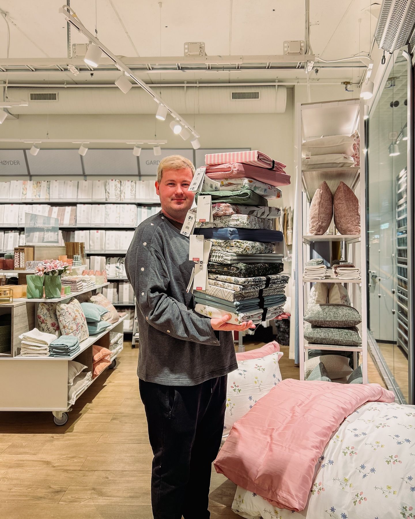 Blid medarbeider hos Princess på ALTI Mandal som viser frem sengetøy