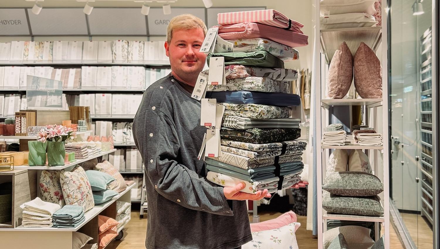Blid medarbeider hos Princess på ALTI Mandal som viser frem sengetøy