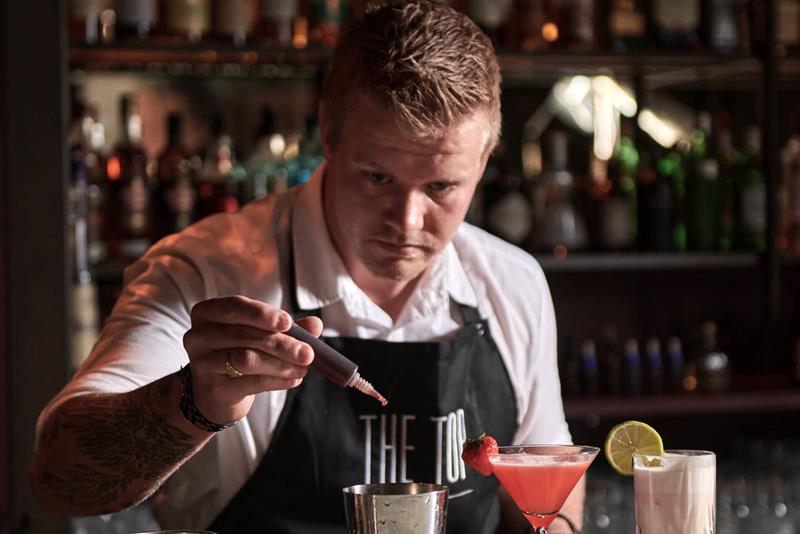 A bartender at The Top dropping ingredients in a shaker.