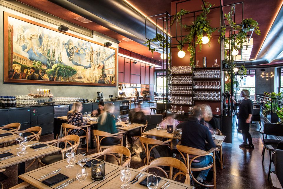 Large painting on the wall, many small tables and chairs.