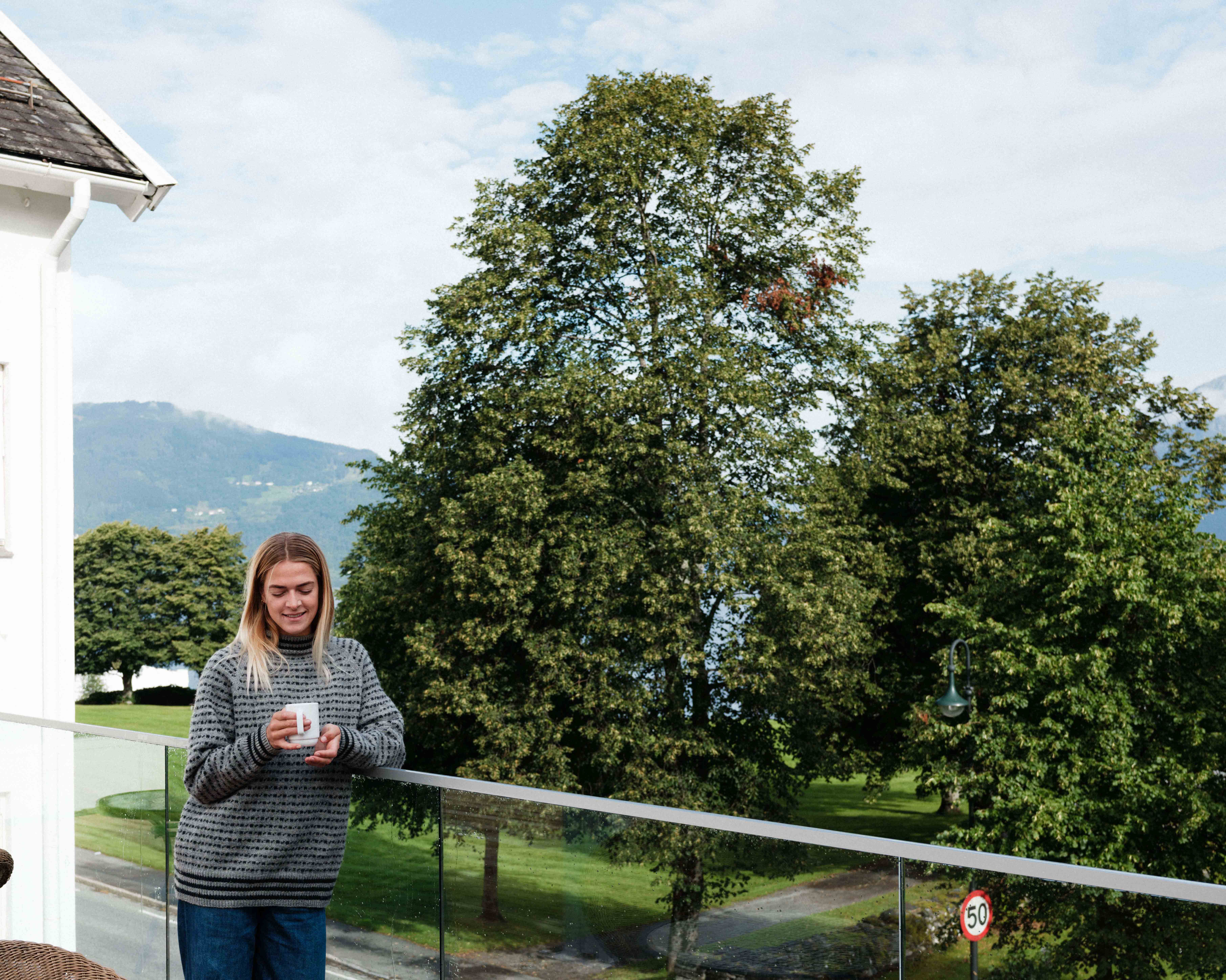 Guest enjoying the scenic view from the outdoor terrace at Kinsarvik Fjordhotel.