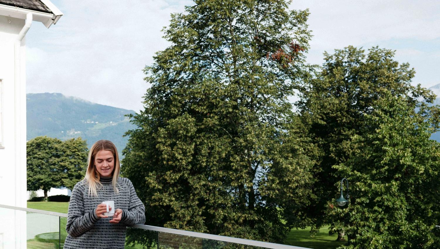 Guest enjoying the scenic view from the outdoor terrace at Kinsarvik Fjordhotel.