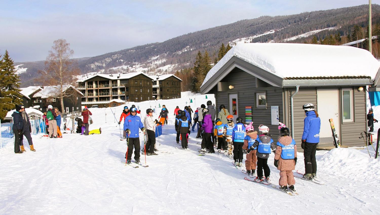 A group of people skiing in front of a building.