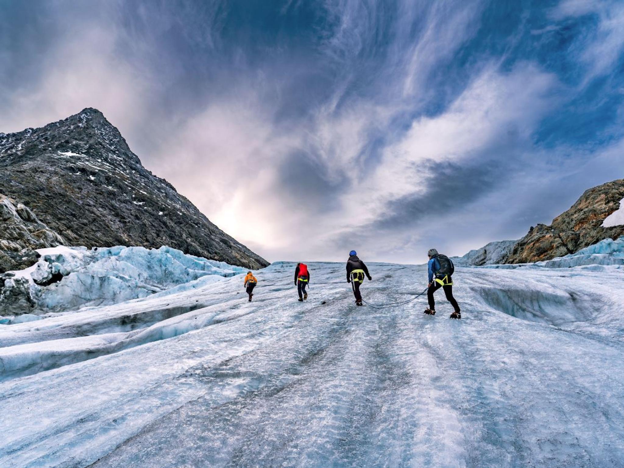 Four persons walking on a glacier