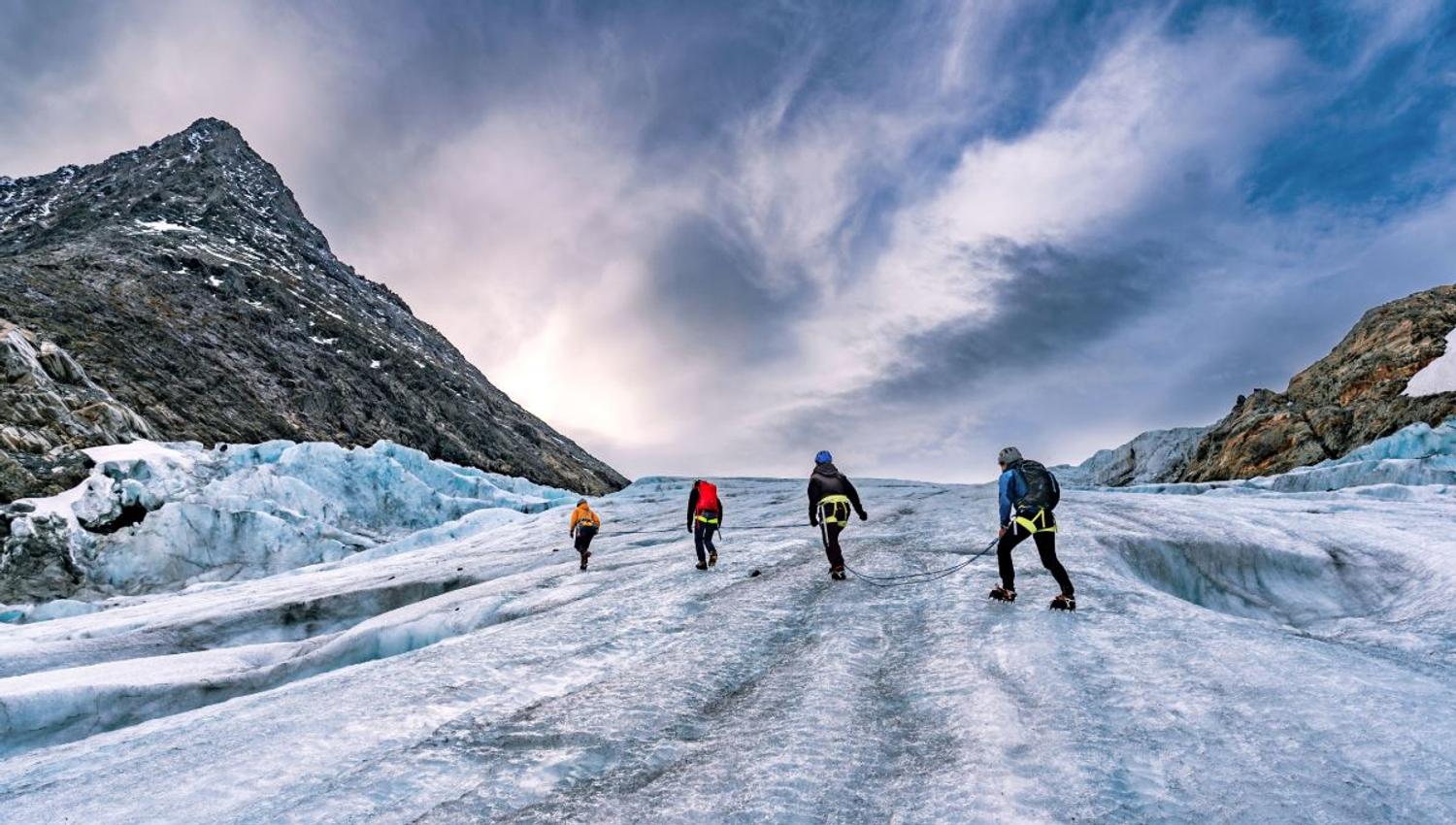 Four persons walking on a glacier