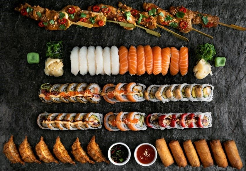 Bilde tatt fra oven av et bord med masse forskjellig sushi, vårruller, dumplings og kylling sticks