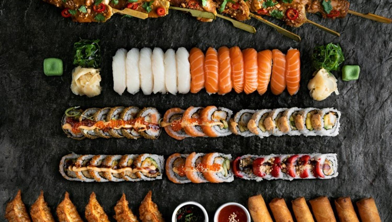 Bilde tatt fra oven av et bord med masse forskjellig sushi, vårruller, dumplings og kylling sticks
