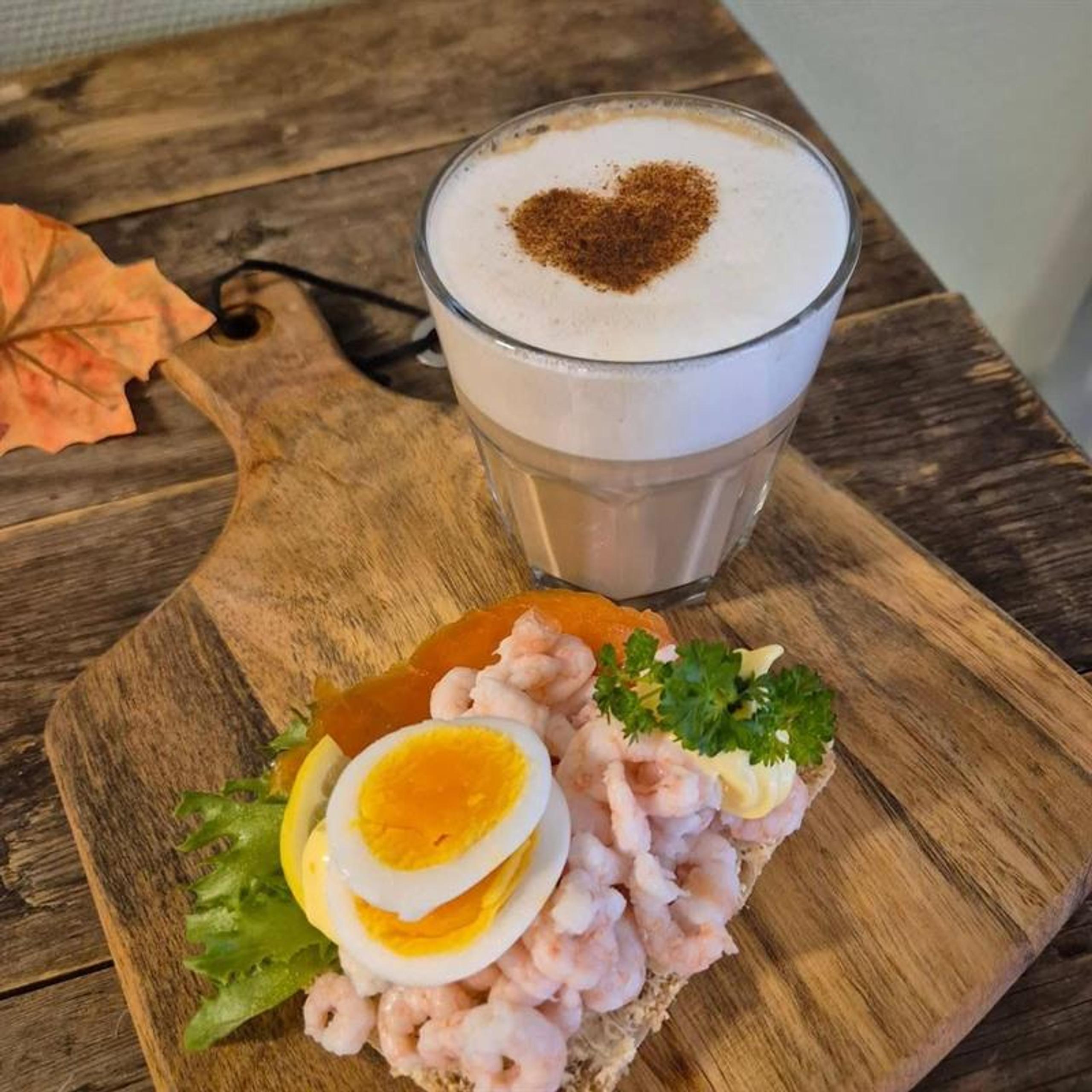 kaffe med hvitt skum og brunt hjerte, smørbrød med reker og egg
