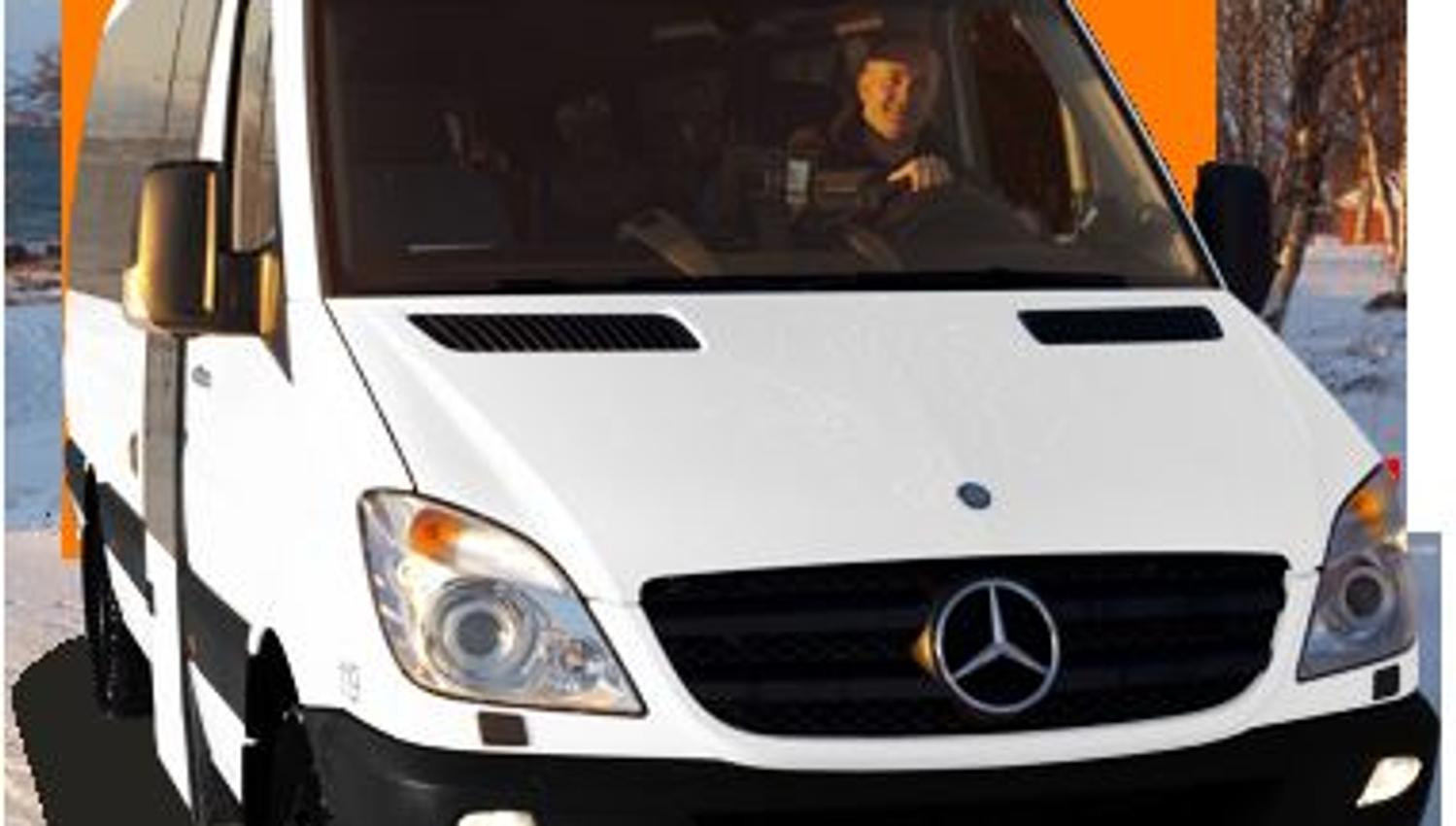 Hvit Mercedes-Benz turvogn med skiltet 'Stein Sørensen', parkert i vinterlandskap med snø og trær i bakgrunnen.