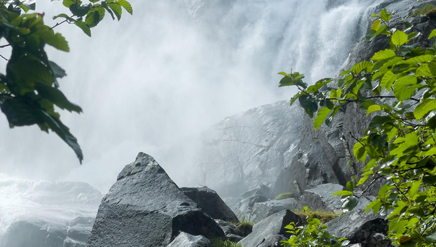 Kraftfull foss i Jordalsdalen, omgitt av grøne tre og stein – ein frisk del av turen til Jordalsnuten.