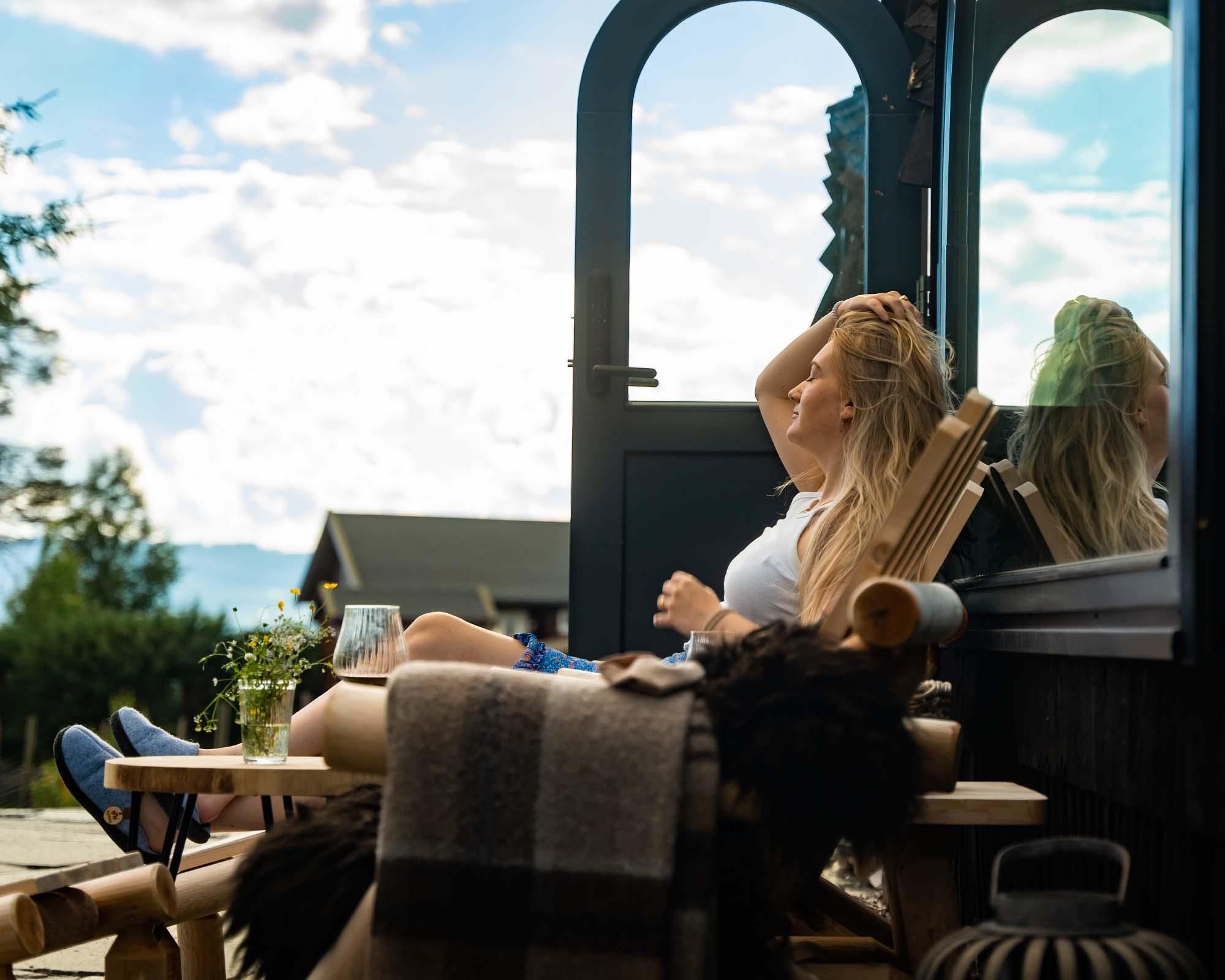 Woman sitting in a chair in front of a cabin with a view.