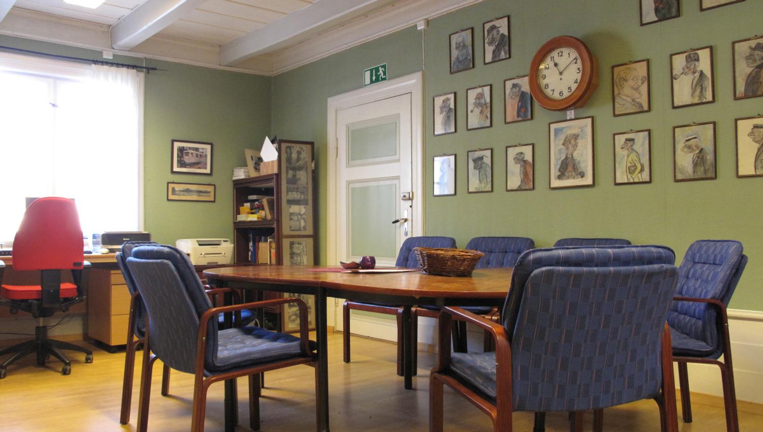 Blå stoler rundt et bord med bilder på veggen