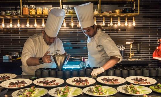 Two chefs preparing dishes to be served in a kitchen