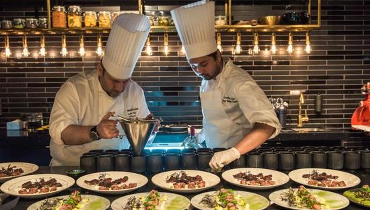 Two chefs preparing dishes to be served in a kitchen