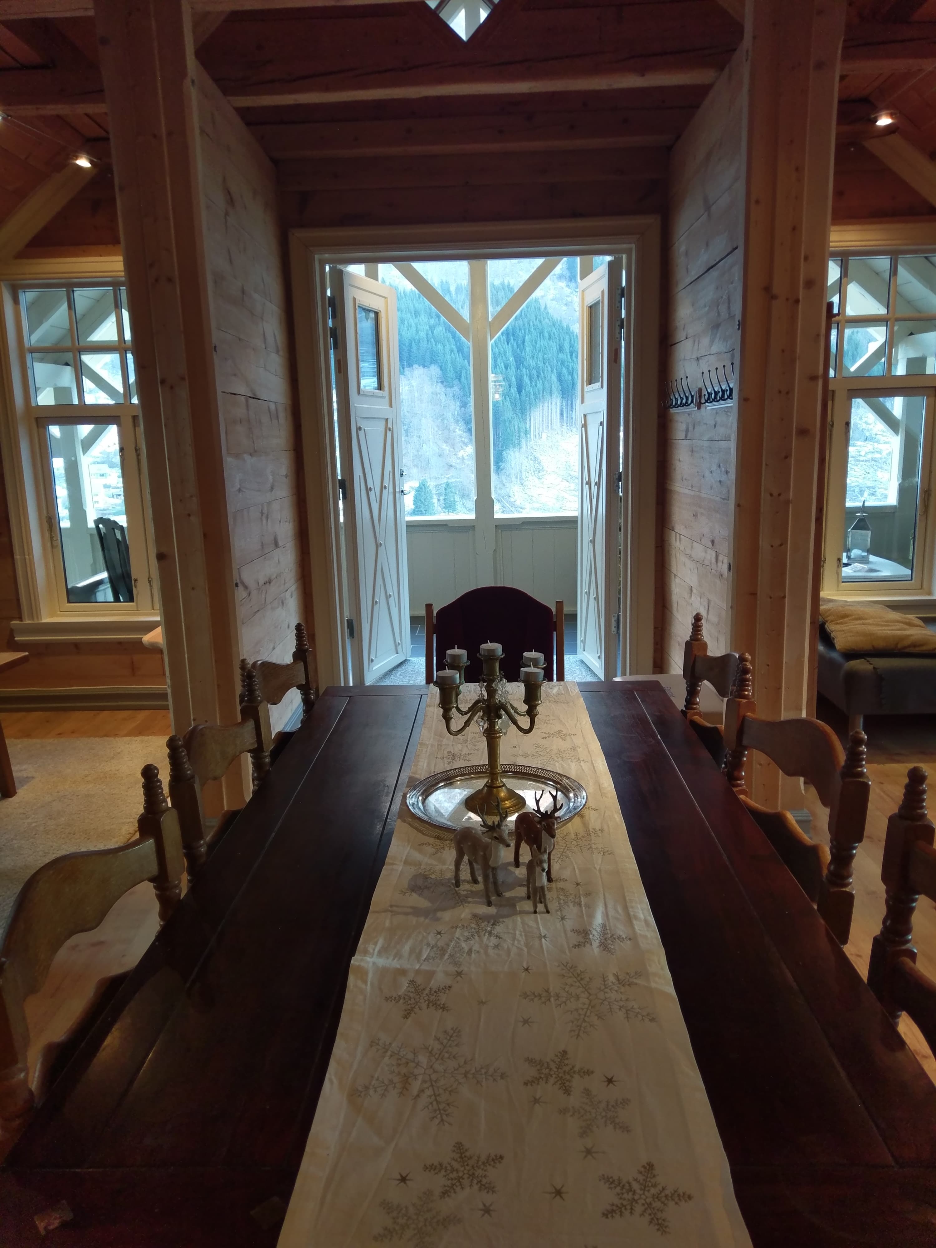 Atmospheric dining room at Vikinghaug Apartments with a long wooden table and views towards the balcony and surrounding mountains.