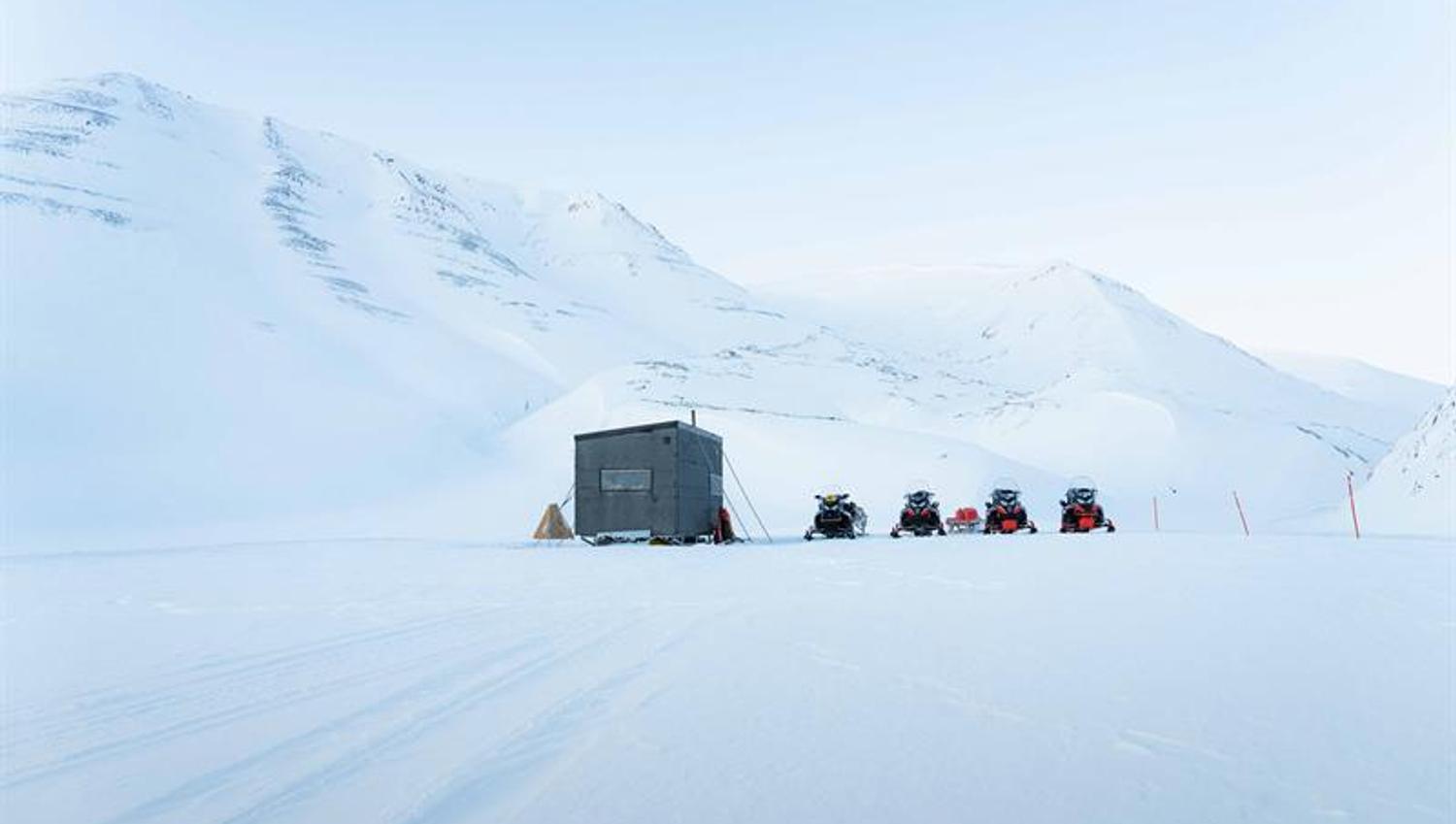 Snøscootere parkert ved siden av en villmarkshytte