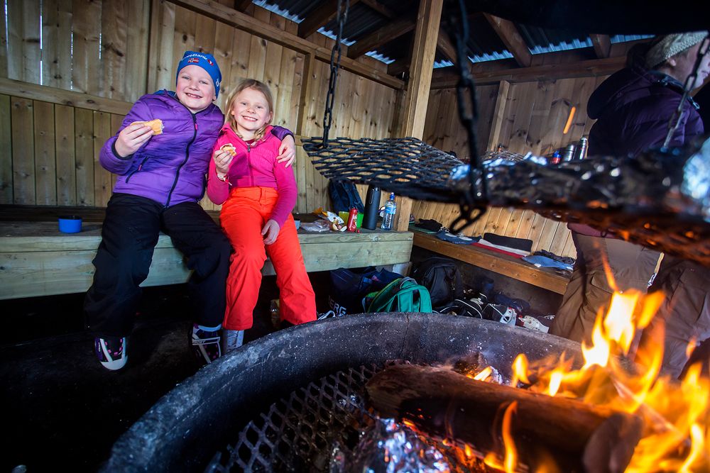 children enjoy sausages at the bonfire place by the skating rink in Skien leisure park