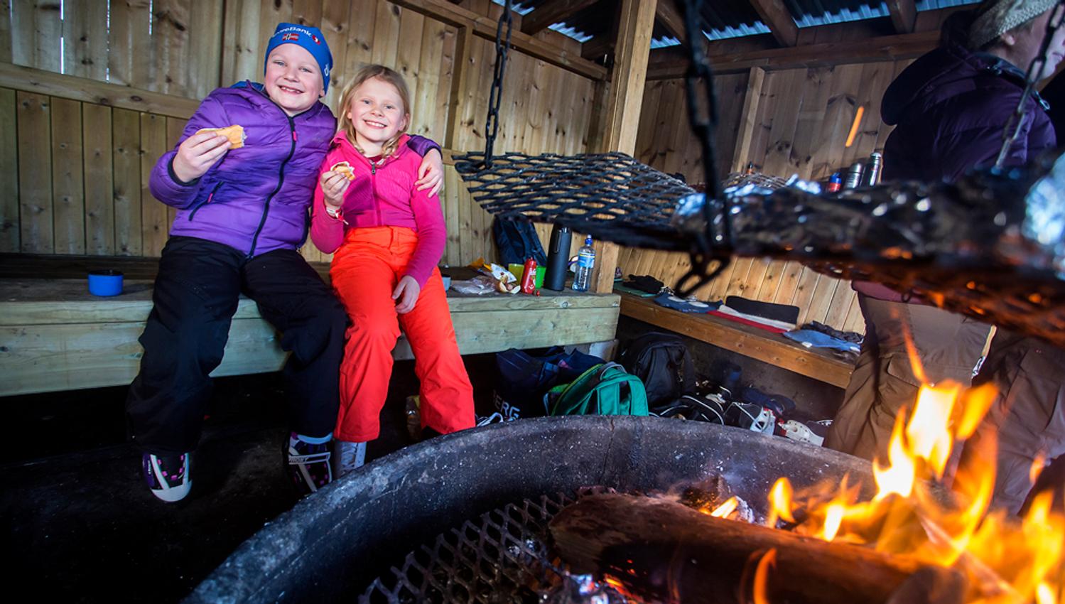 children enjoy sausages at the bonfire place by the skating rink in Skien leisure park