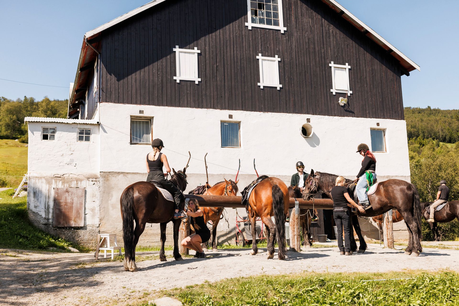 Riders have stopped in front of the barn. 