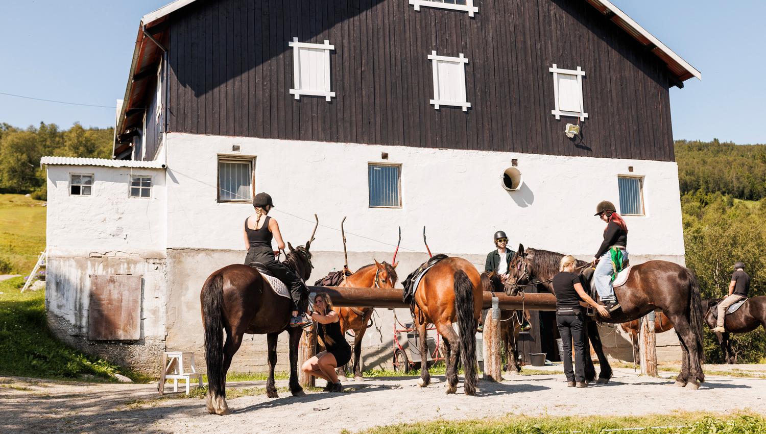 Riders have stopped in front of the barn.