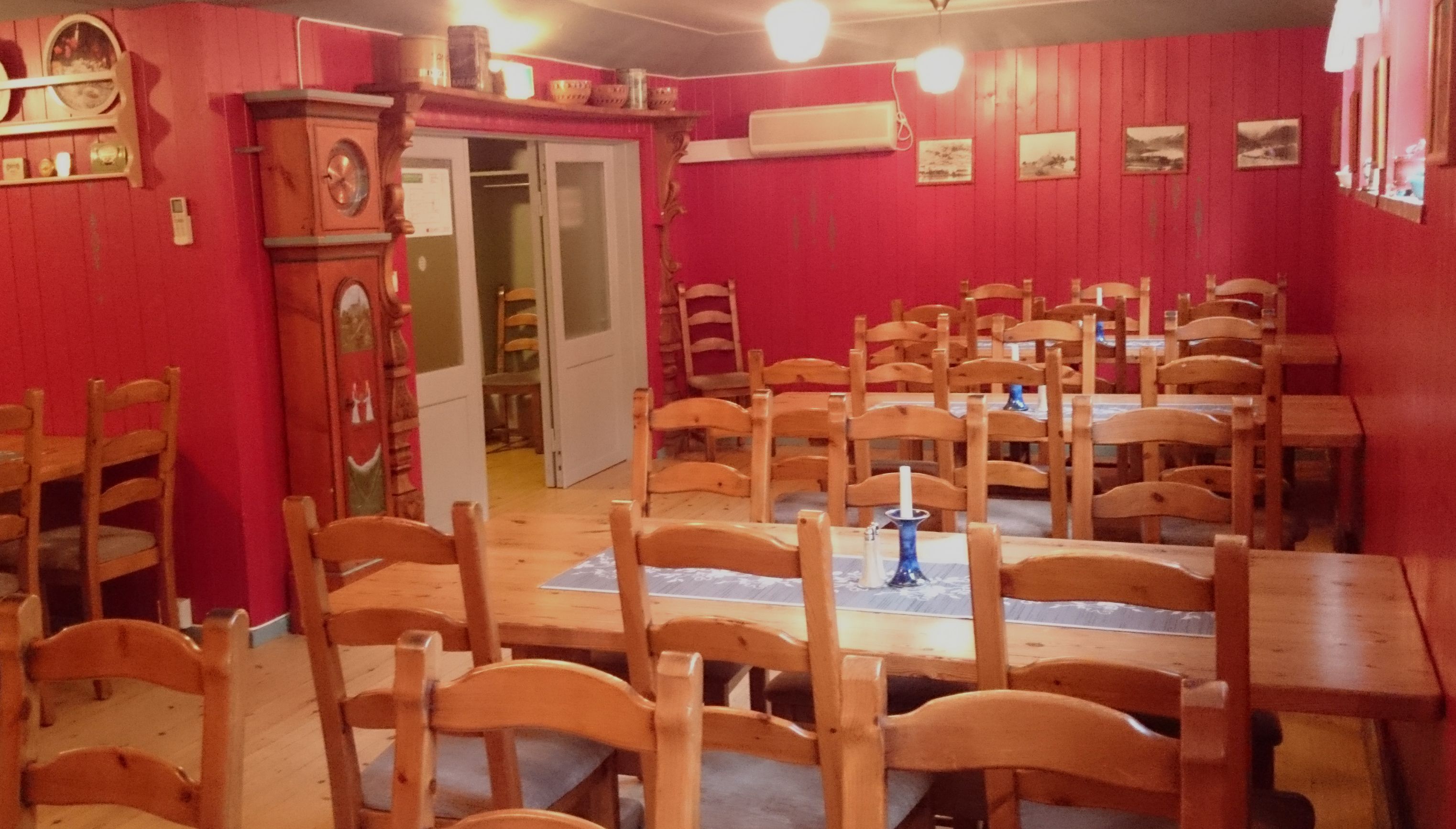 Spacious dining room with long wooden tables and chairs at Ullensvang Gjesteheim, decorated with warm colors and historic details.