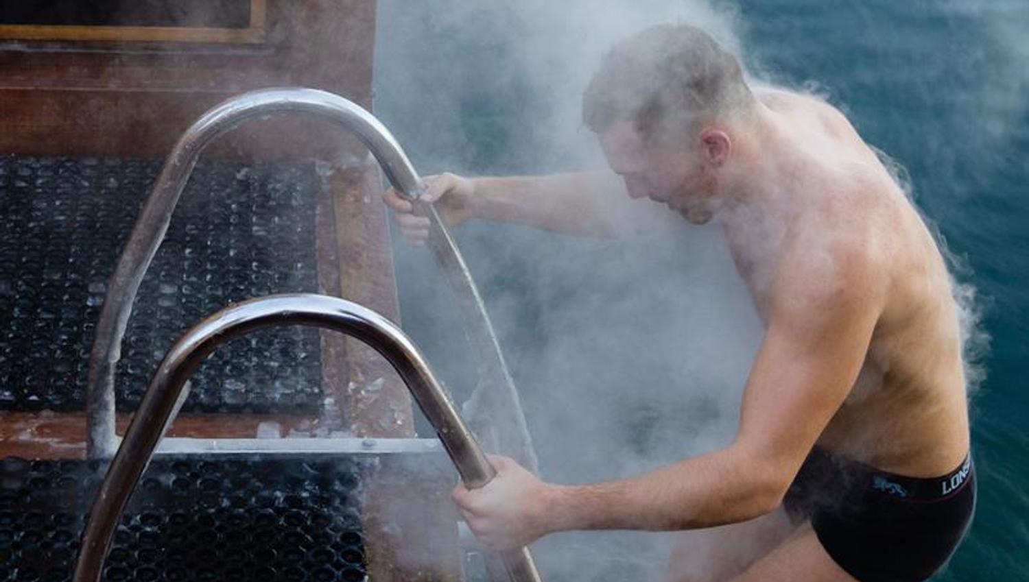 A man on his way to swim in the fjord during winter