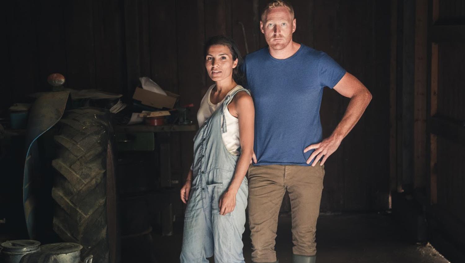 A couple running Edel Sider, standing in a dimly lit cider house, ready for work.