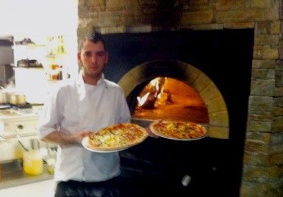 Kokk med pizza på vei inn i steinovnen