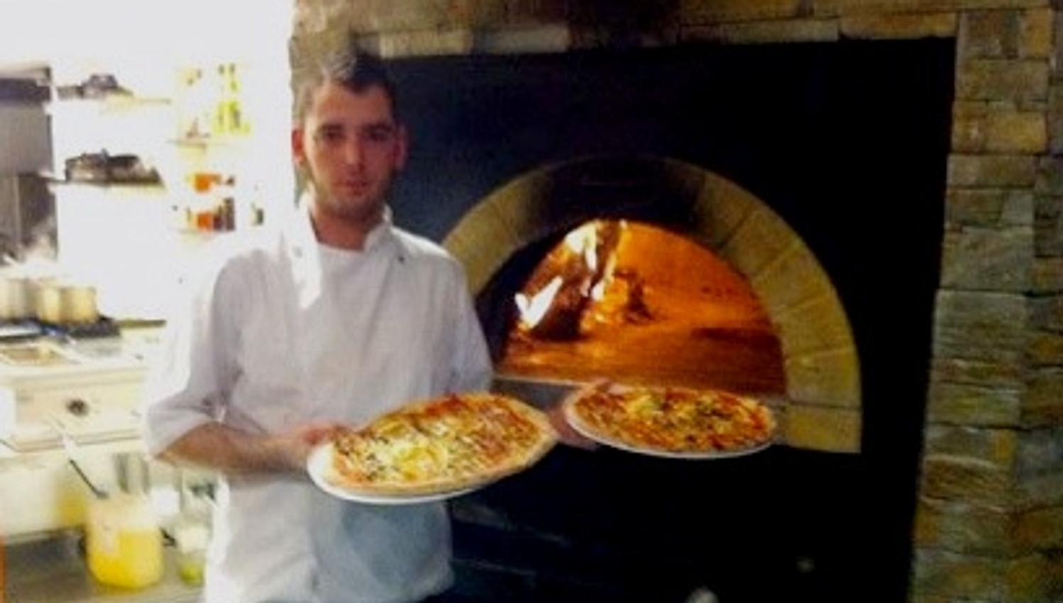Kokk med pizza på vei inn i steinovnen
