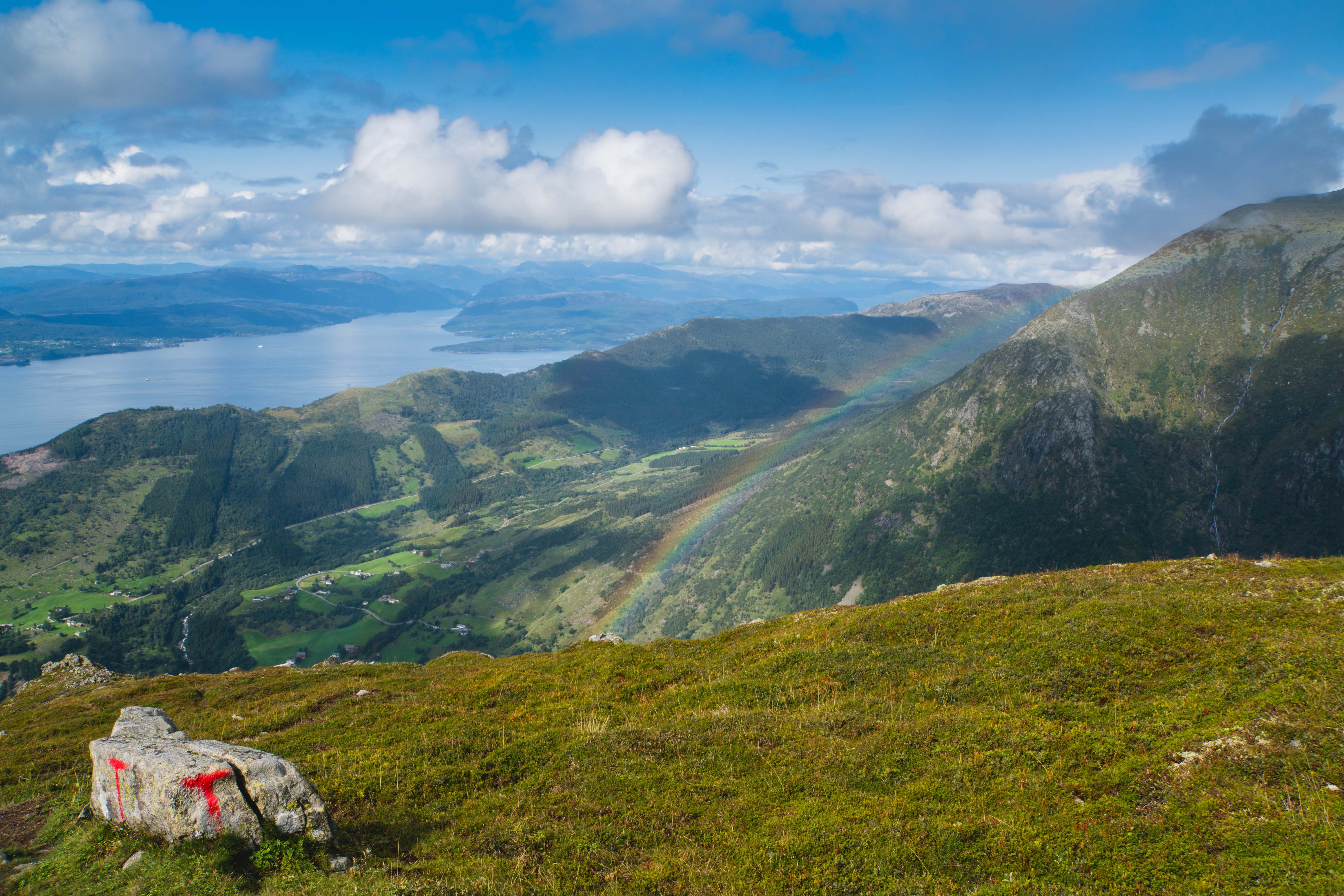 Fargerik regnboge som strekkjer seg over fjellsida ved Malmangernuten med utsyn mot Hardangerfjorden.
