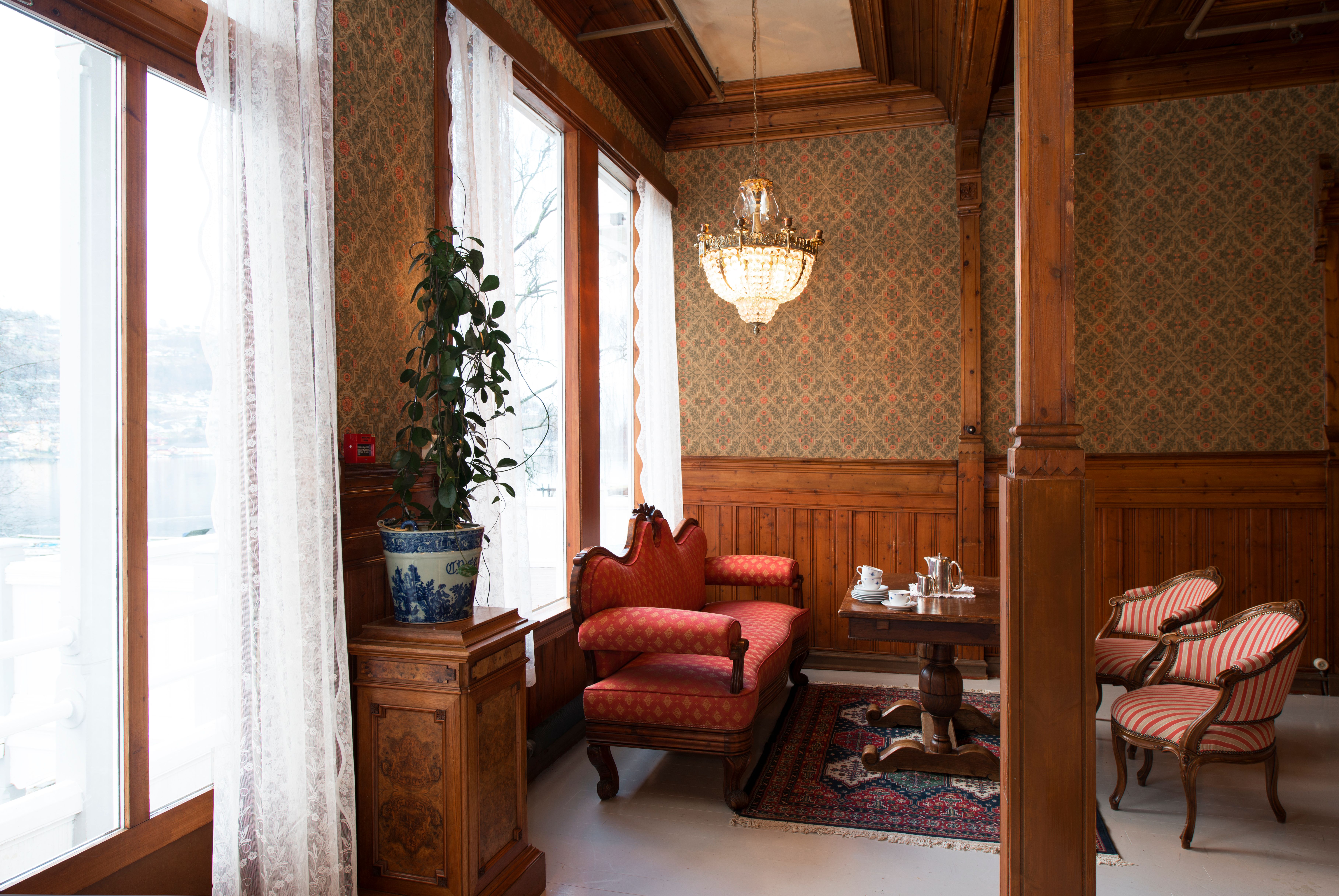 Elegant lounge at Thon Hotel Sandven, featuring historic furnishings and a view of the Hardangerfjord.