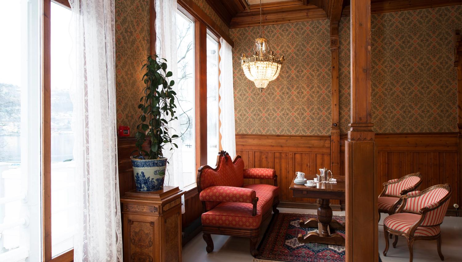 Elegant lounge at Thon Hotel Sandven, featuring historic furnishings and a view of the Hardangerfjord.