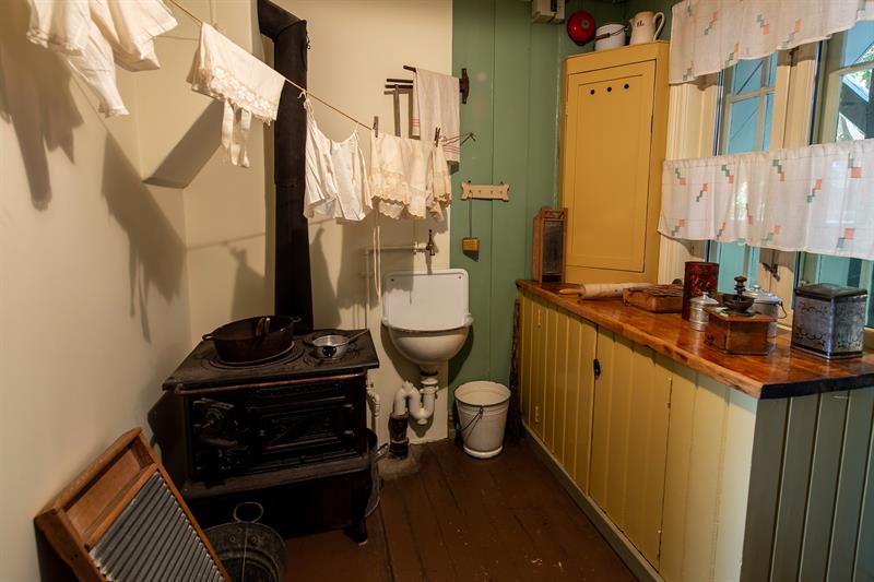 Reconstructed kitchen interior with a wood-burning stove, drying laundry and historic kitchen utensils from an older workers’ home.