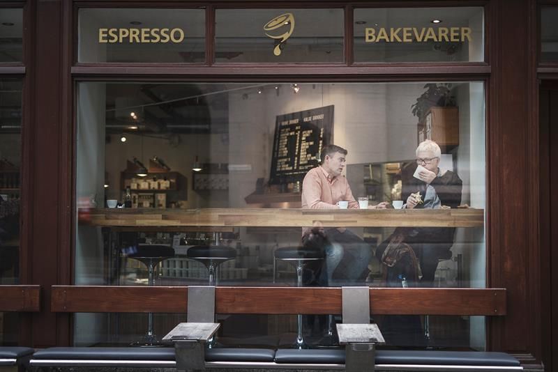 two people sitting by the window talking to each other