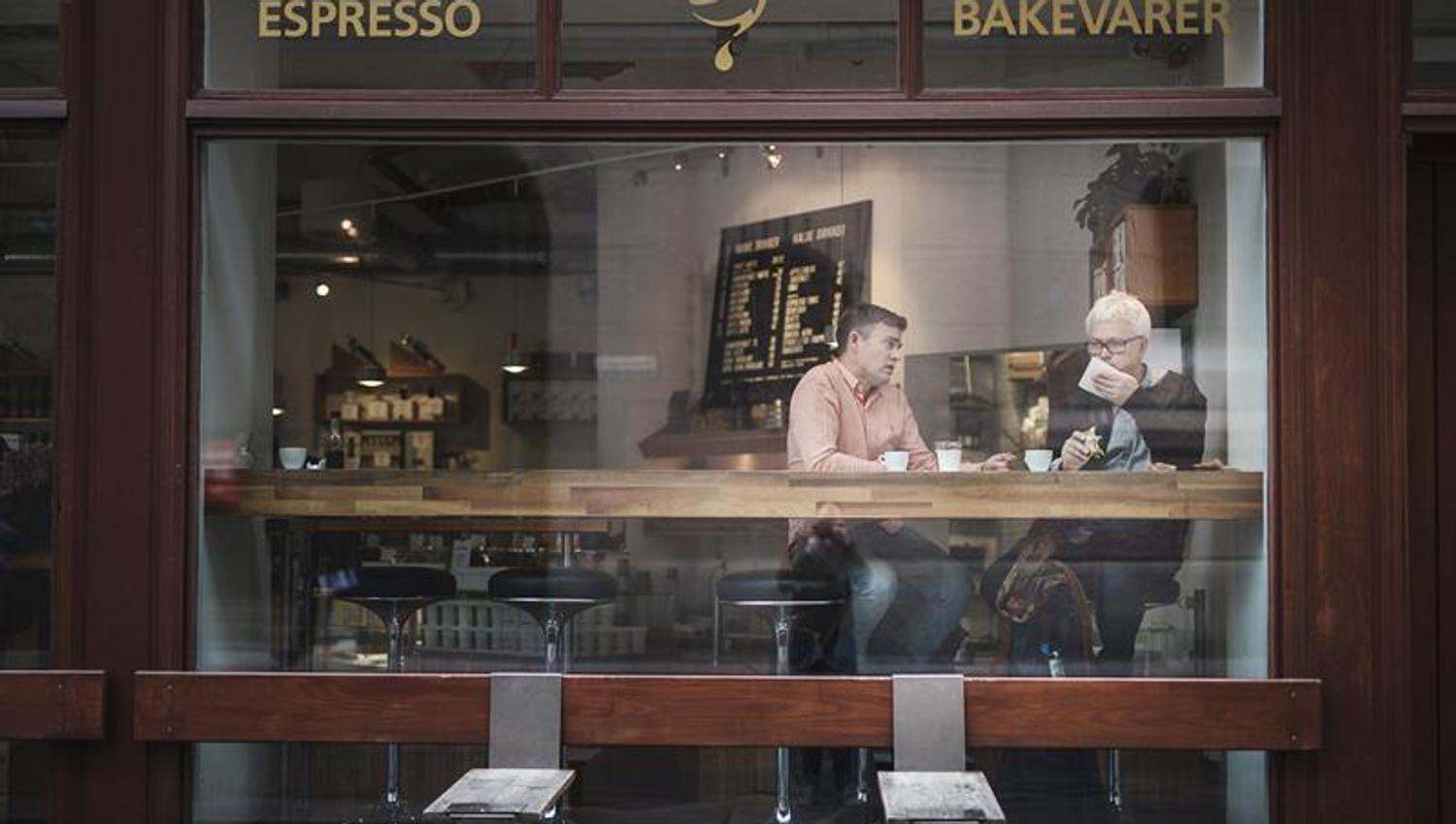 two people sitting by the window talking to each other