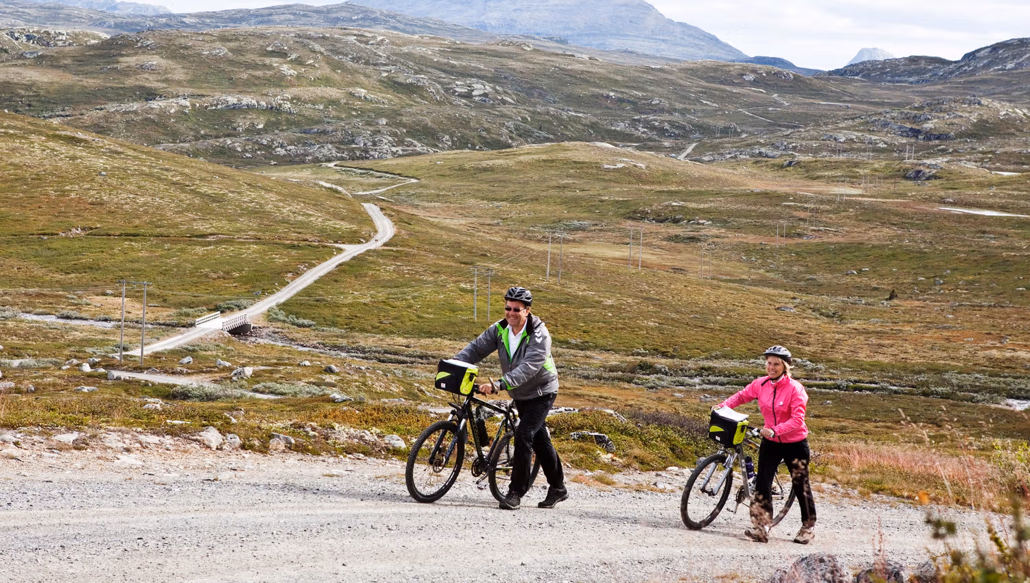 eldre par dytter syklene sine og Gaustatoppen i bakgrunn