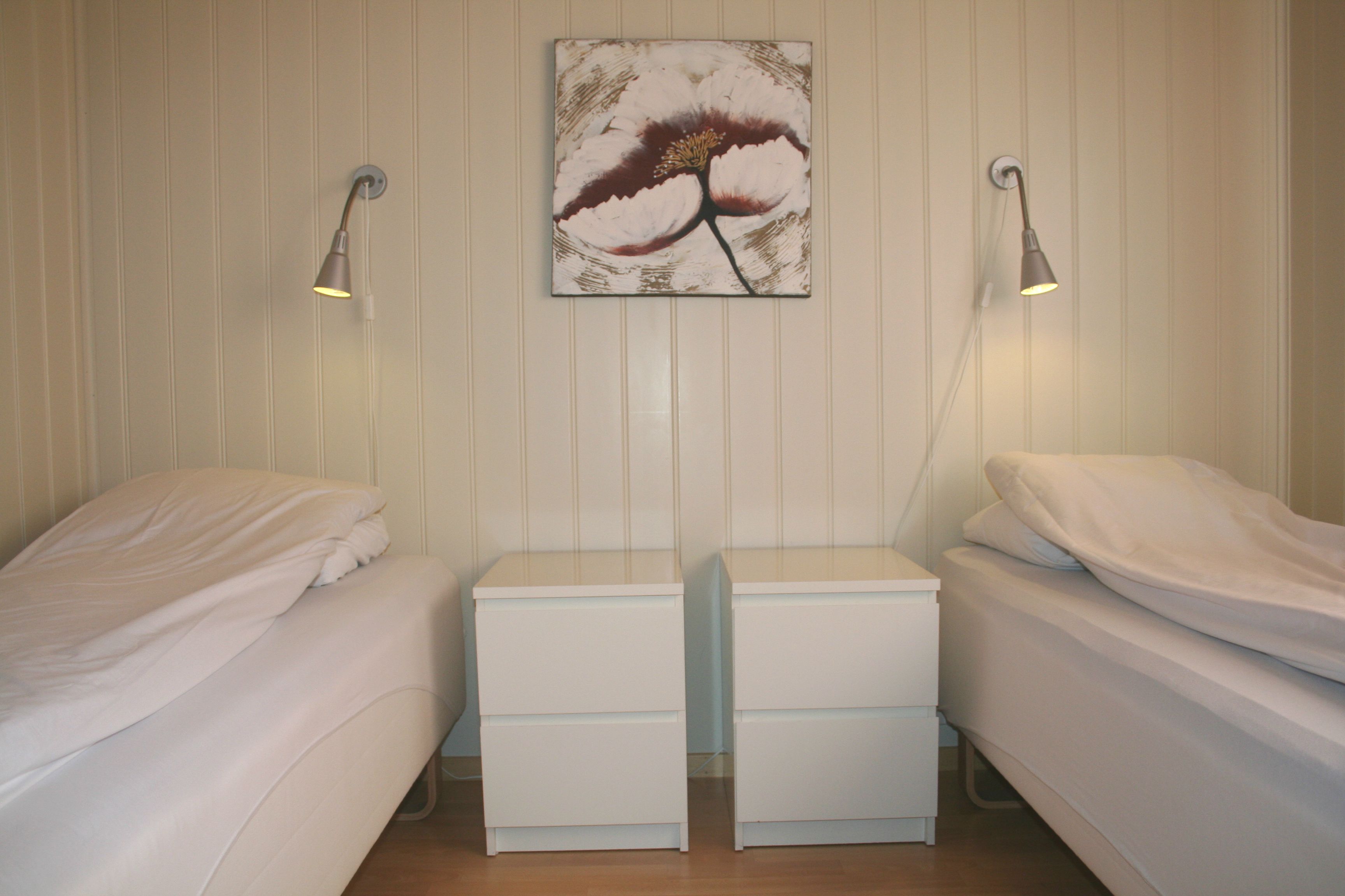 Bedroom with two single beds and wall art in a cabin at Oddland Camping.