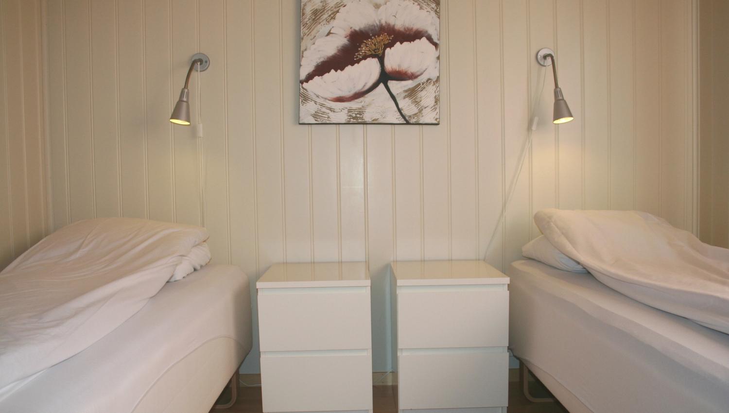 Bedroom with two single beds and wall art in a cabin at Oddland Camping.